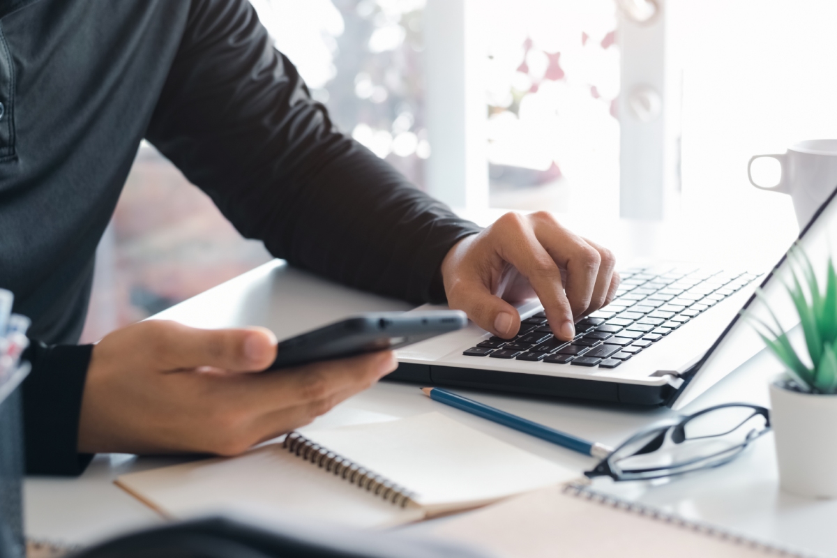 Personne au bureau avec ordinateur et smartphone, formulaire de contact